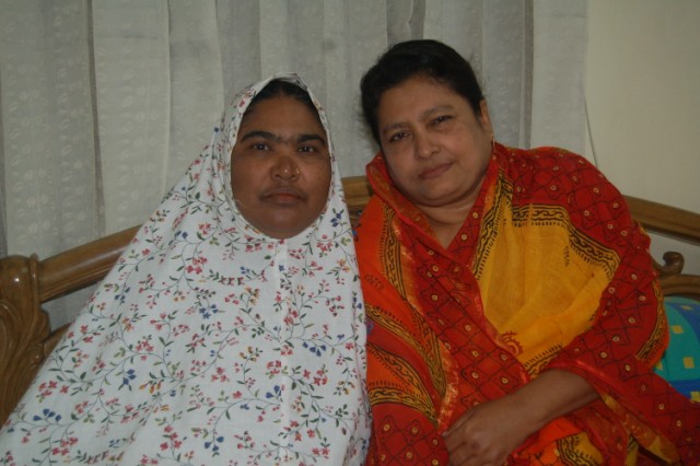 two women are wearing brightly colored clothing and one is sitting on her stomach