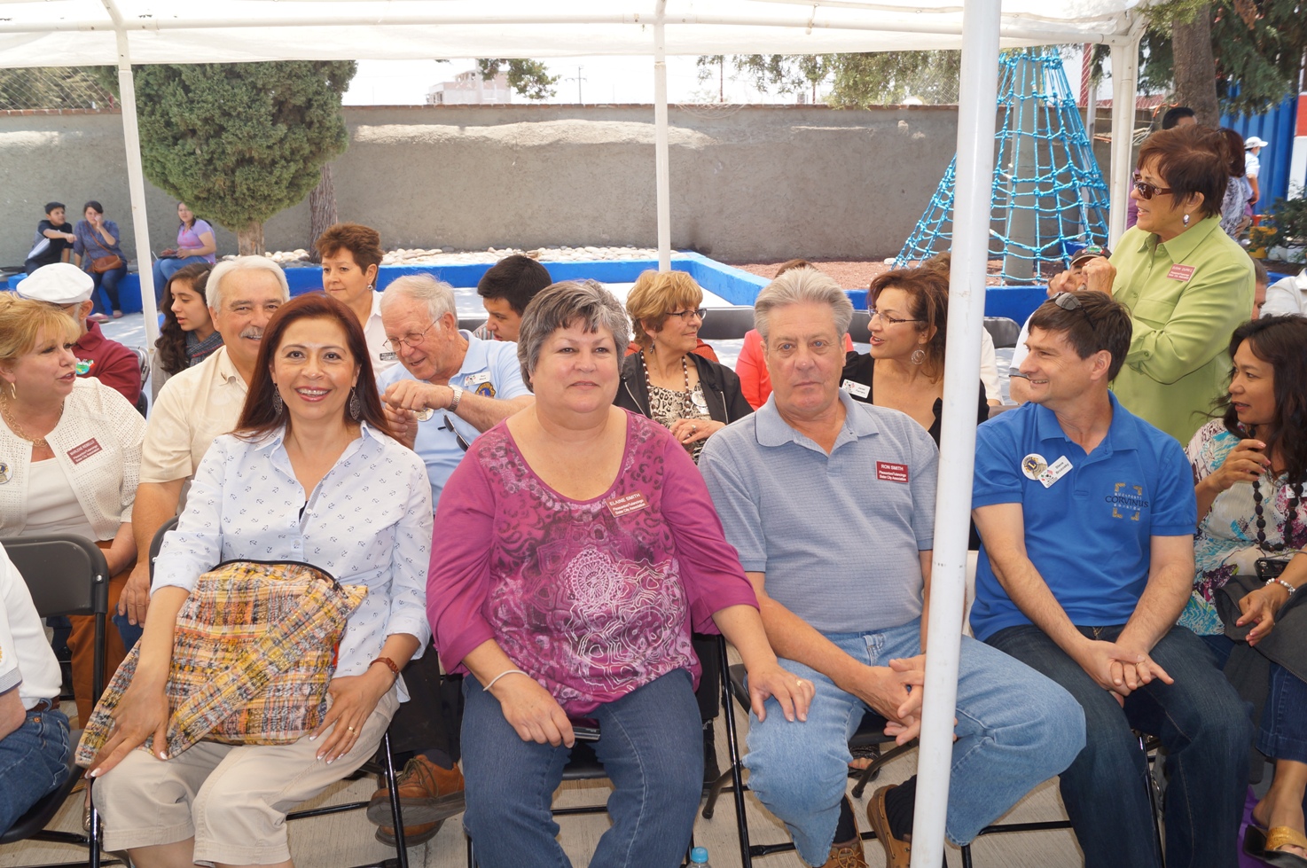 group of people sitting in chairs beneath an umbrella