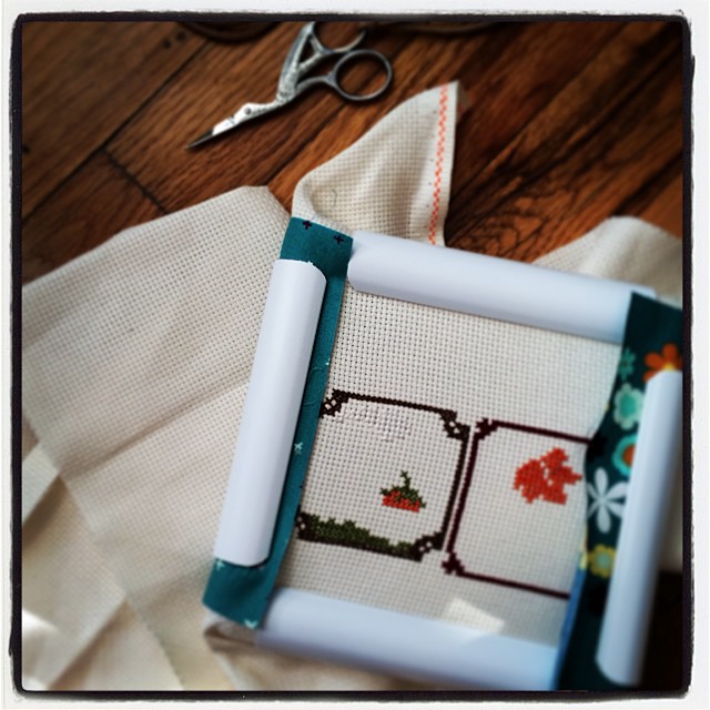 a cross stitch picture frame sitting next to some sewing scissors
