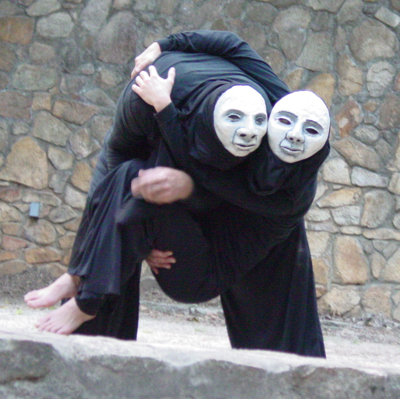 a woman in a black cloak hugging a man wearing white masks