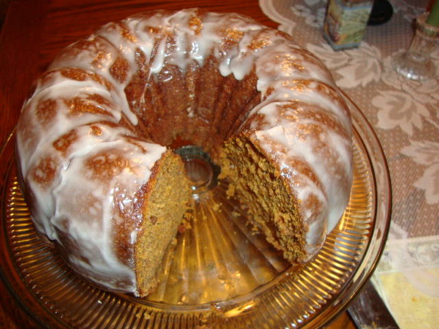 a bundt cake sits on a platter with a slice removed from it