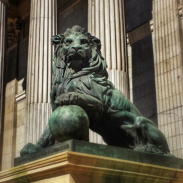 a bronze lion statue stands between tall pillars