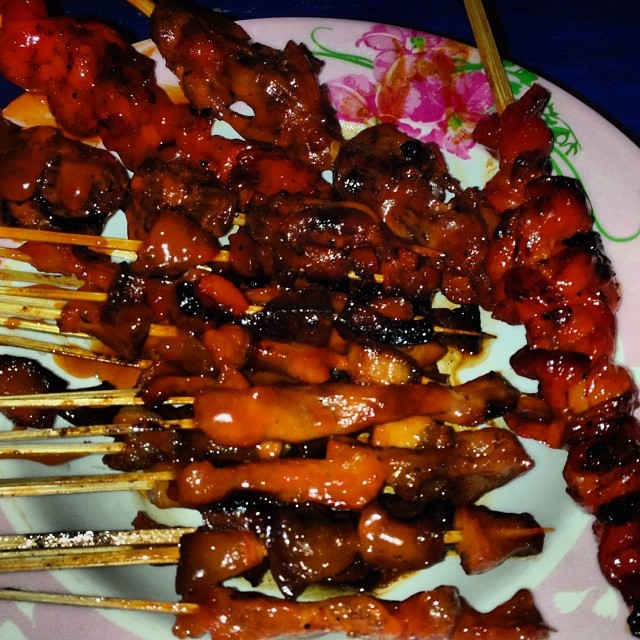 barbecues and skewers on pink plate sitting on table
