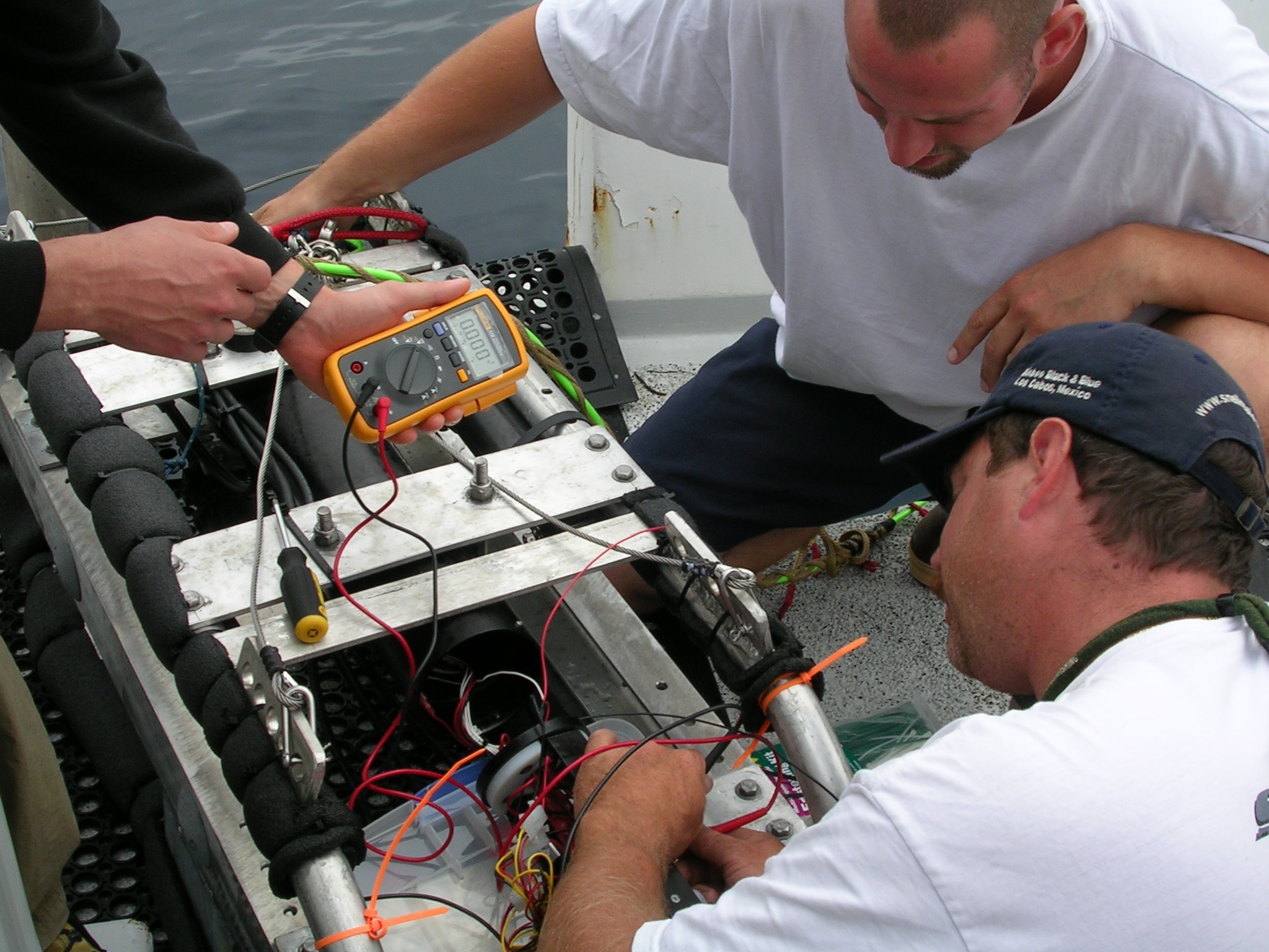 two men working on an engine that is in the ocean