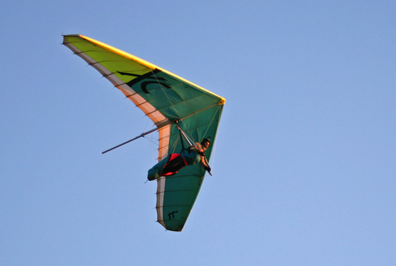 man in green outfit gliding in green and yellow kite
