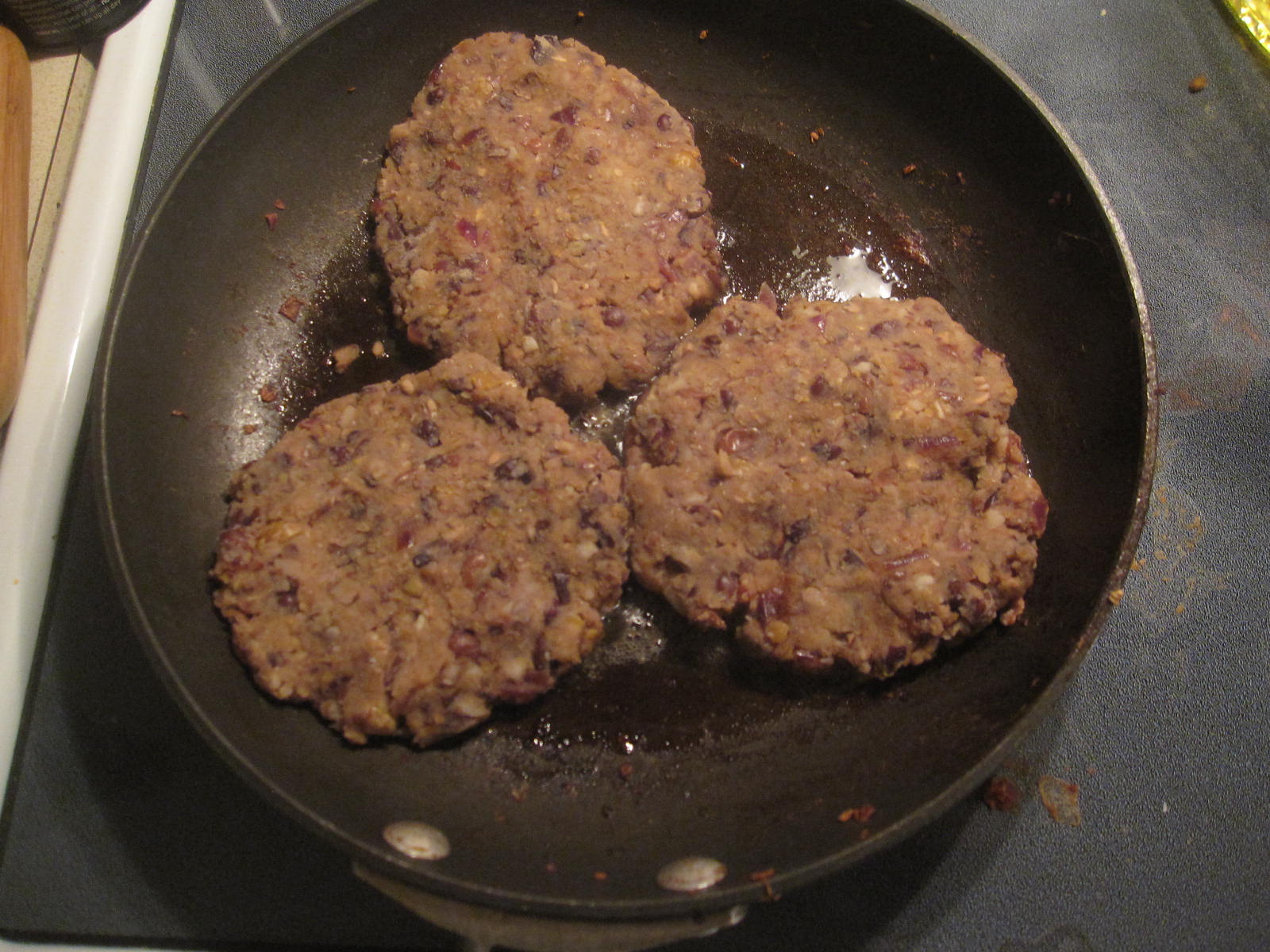 four meat patties cooking in a wok