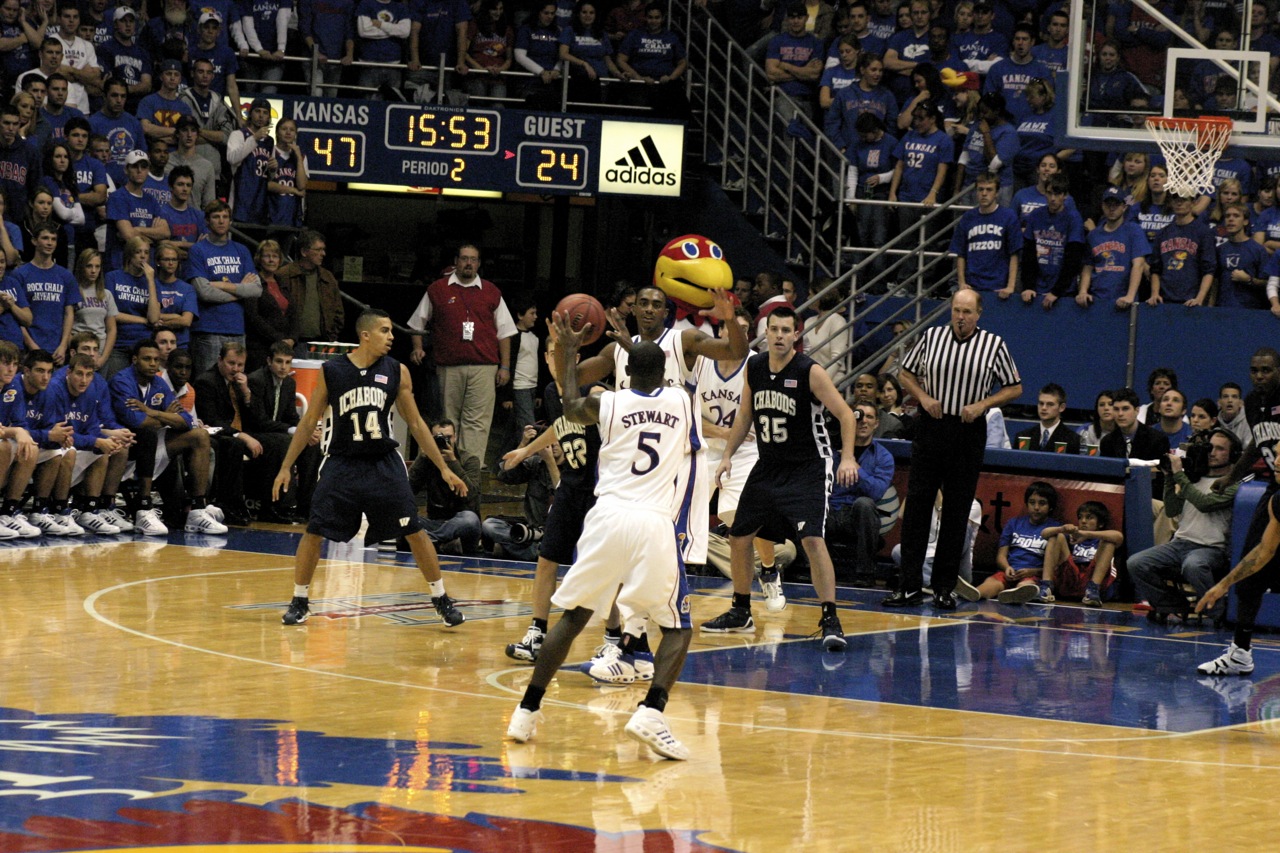 two teams playing a game of basketball while fans watch
