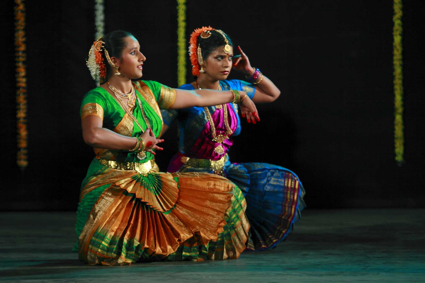 two women in colorful costume are doing a dance