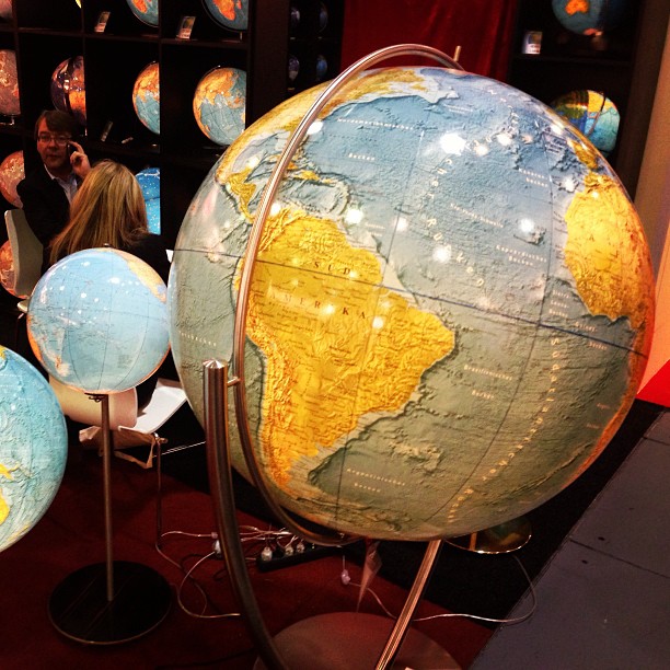 a child takes pictures of an earth globe with people standing nearby