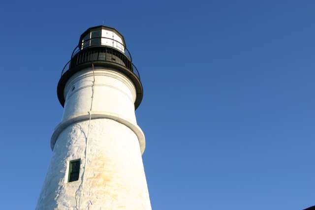 a white lighthouse on the coast in clear skies