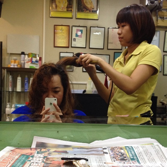 two women at a hair salon using their phones