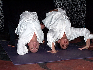 two people doing a handstand on some mats