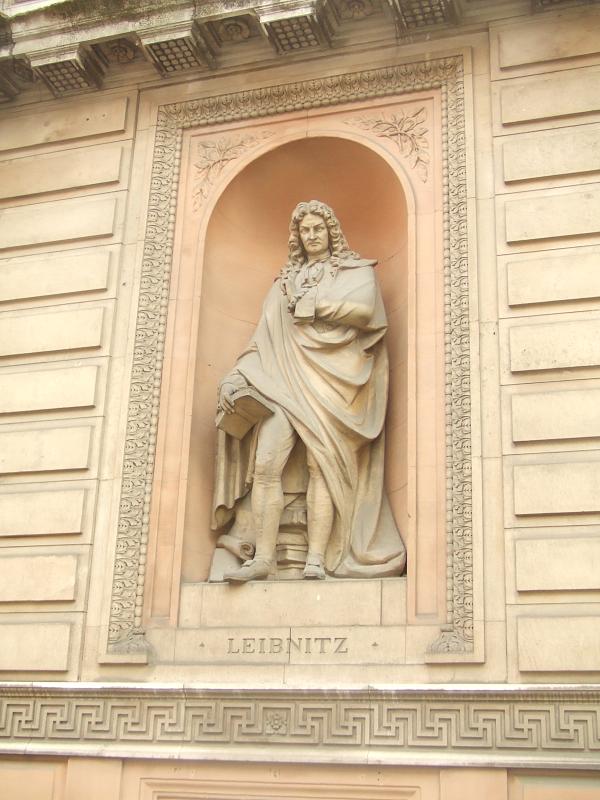 the monument on the side of the building has a statue of a man in a cloak