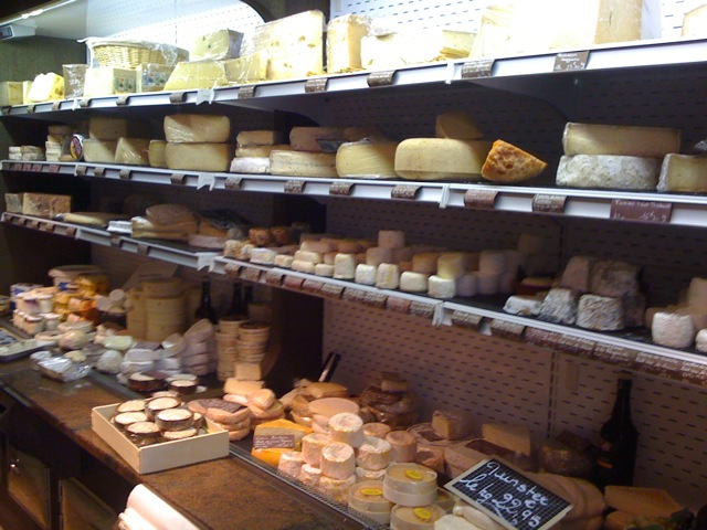 there is a display with cheeses in the shop