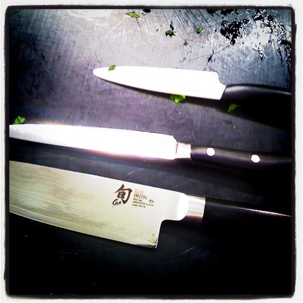 two chefs knives with black handles, one being cut up and the other is on