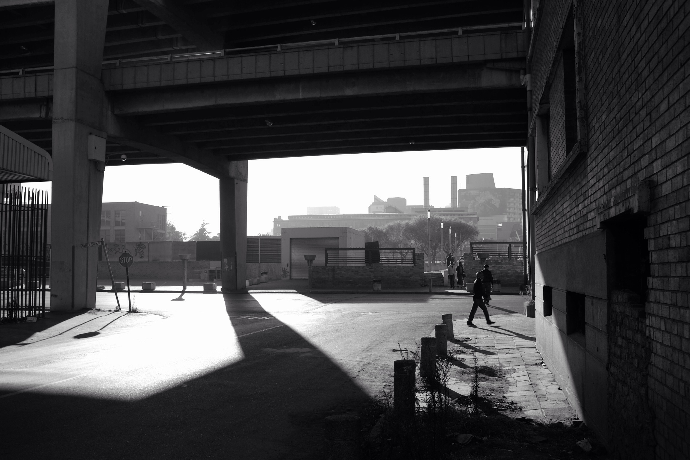 black and white pograph of a person walking on a street near a bridge