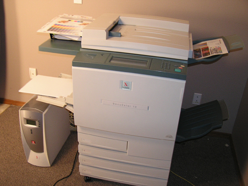 a desk with a paper cutter, printer and other items