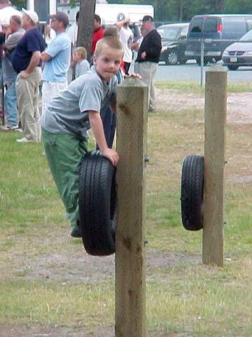 the boy is playing on the tire obstacle