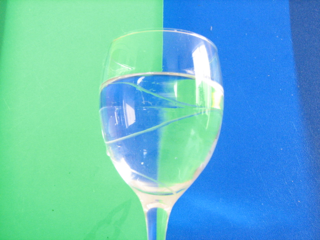 glass of white wine on table against blue and green wall