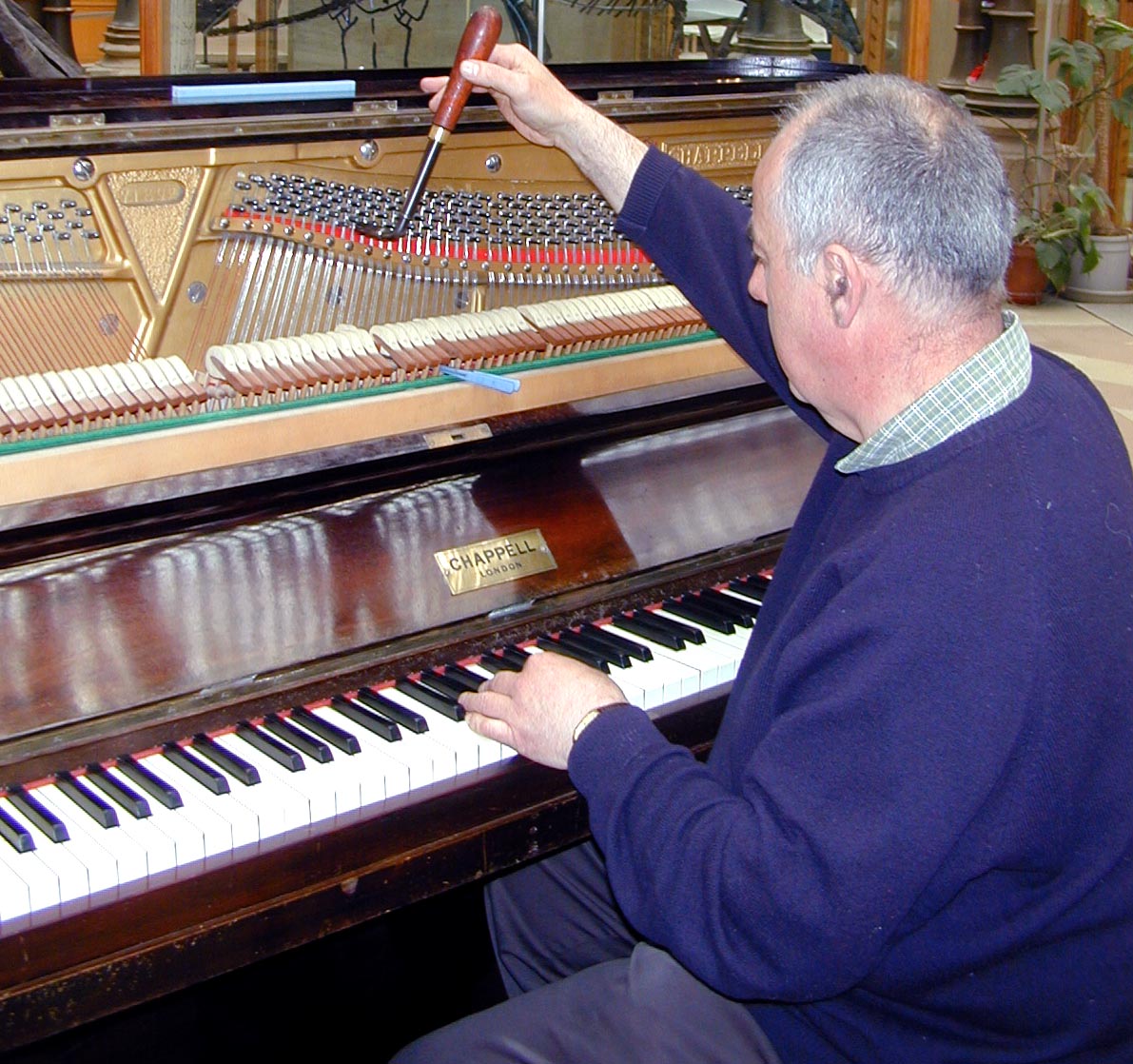 a man with a microphone sitting at a piano