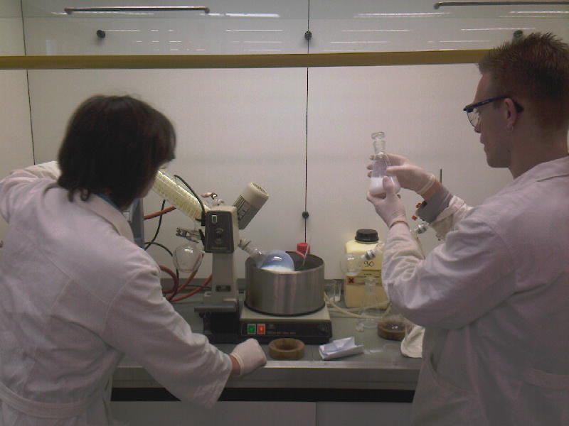 two people in white lab coats cooking in a kitchen