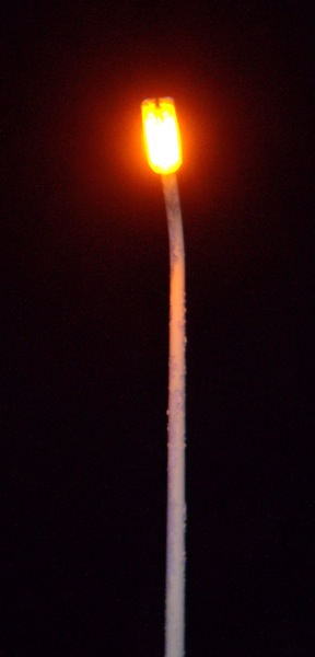 a white pole and a red light in the dark