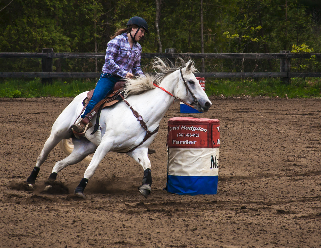a person that is riding a horse around a barrel