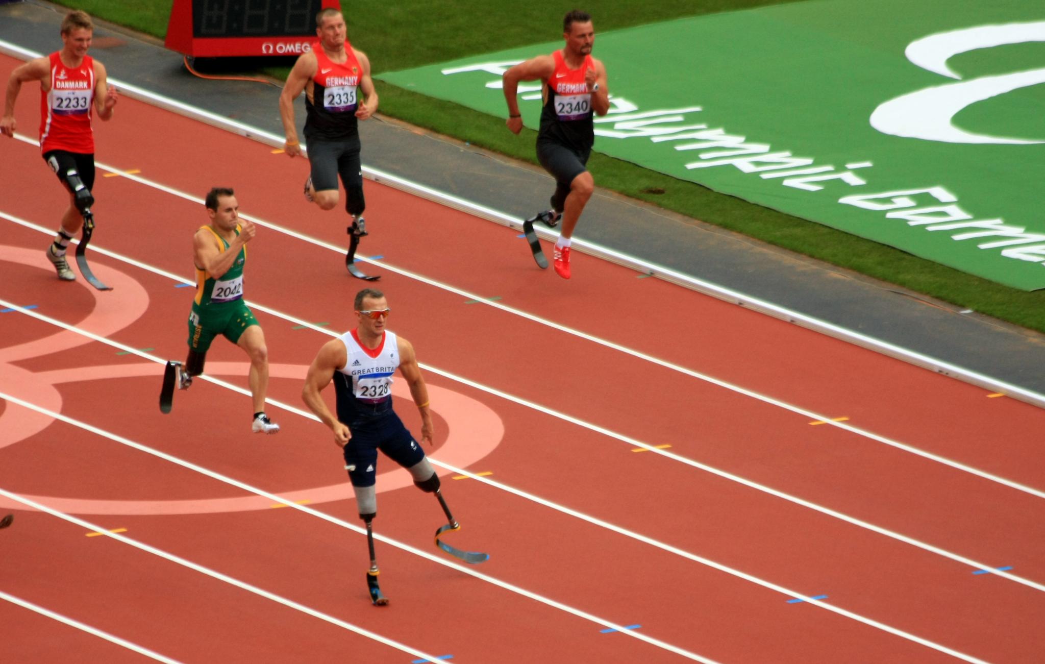 four athletes in uniforms on a running track