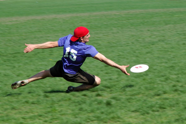 a man in a red cap tries to catch a white frisbee