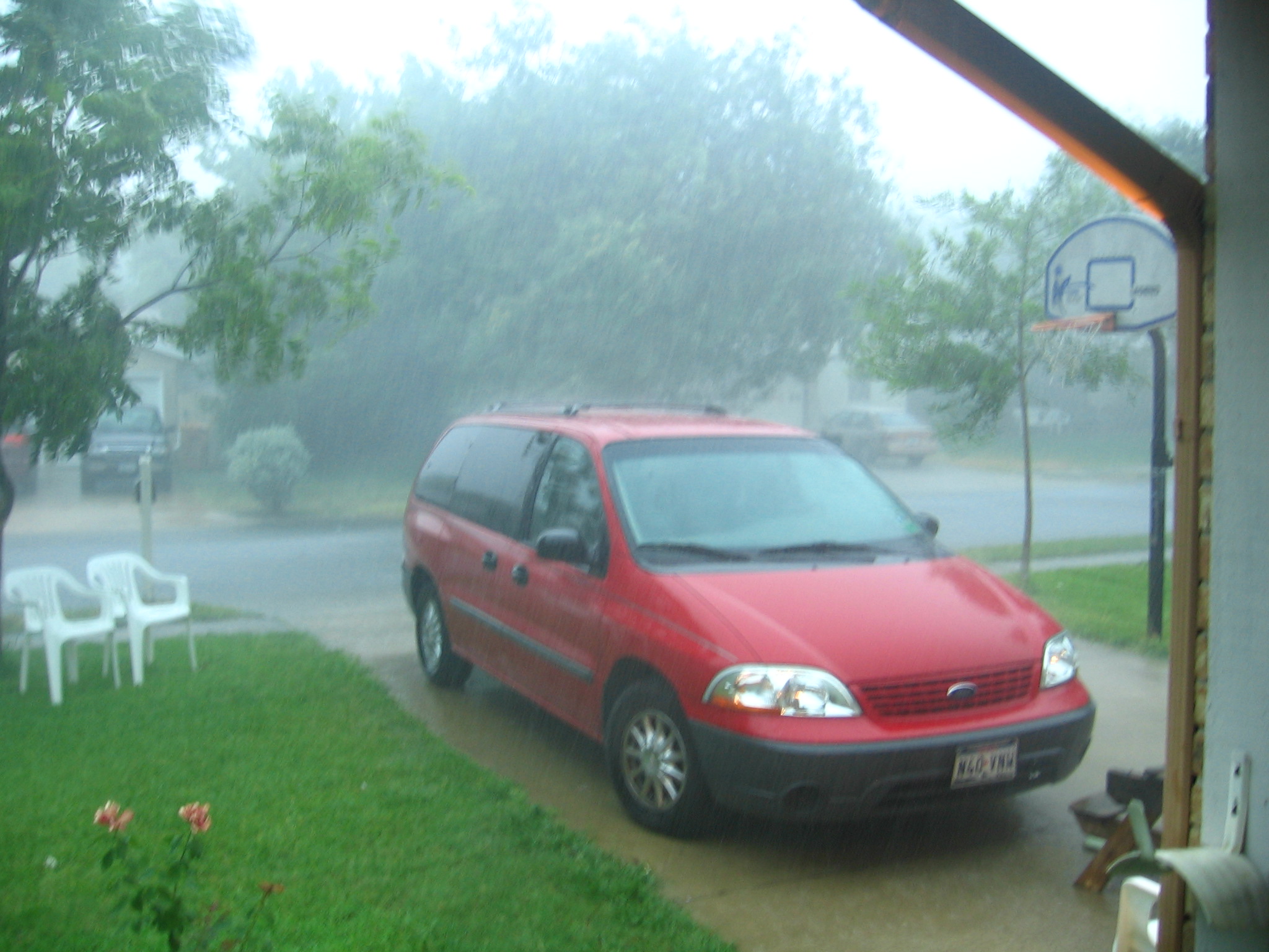 a red vehicle on the road in front of a house