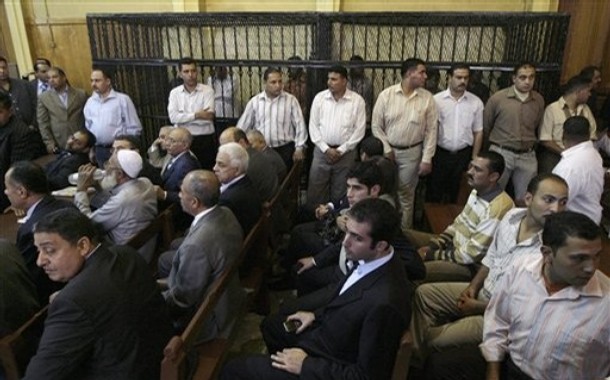 several men in suits are sitting in chairs, with their backs turned towards one another