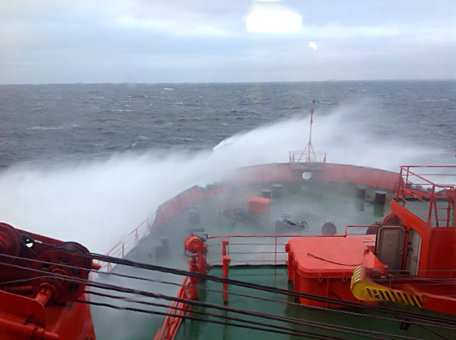 waves crash over and off of the bow of a ship