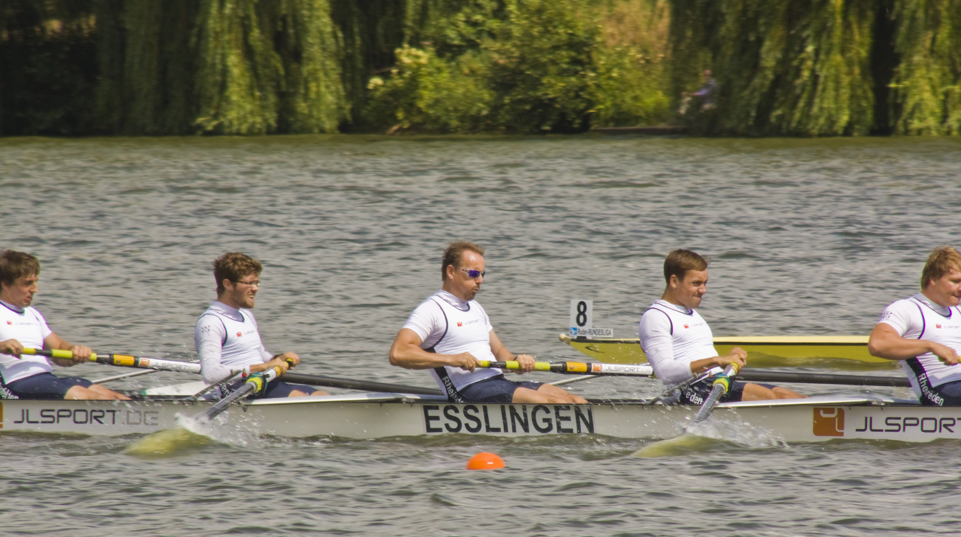 five people on the back of a boat rowing on the water