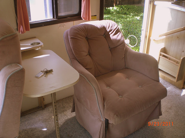 a pink recliner chair is in a room with a table and a chair