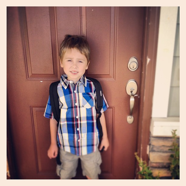a boy posing for a picture outside of a door