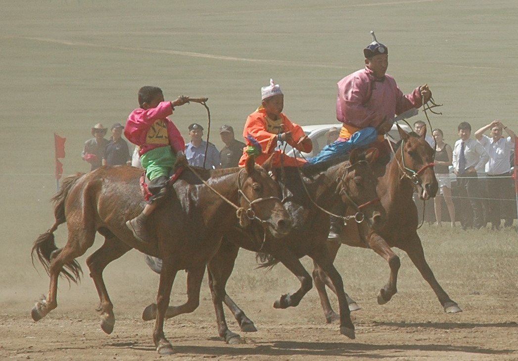 a group of people riding horses in the dirt