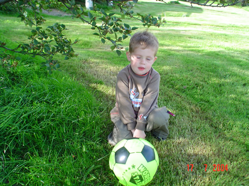a little boy kneeling down in front of a soccer ball