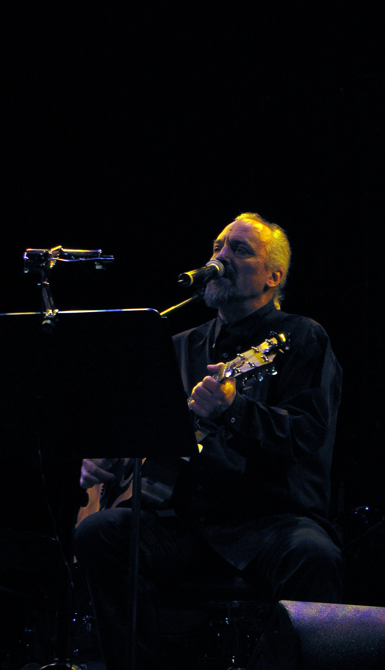 a man playing a guitar while performing in front of microphones