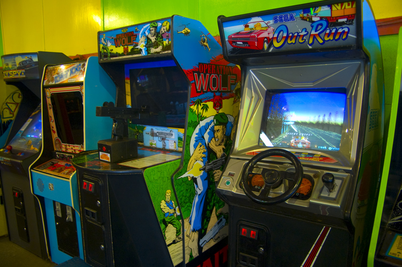 arcade games and gaming machines displayed against a green wall