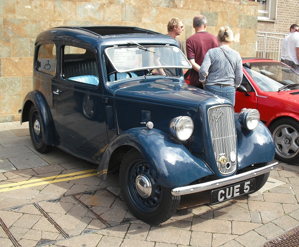 an antique blue car is parked in front of some people