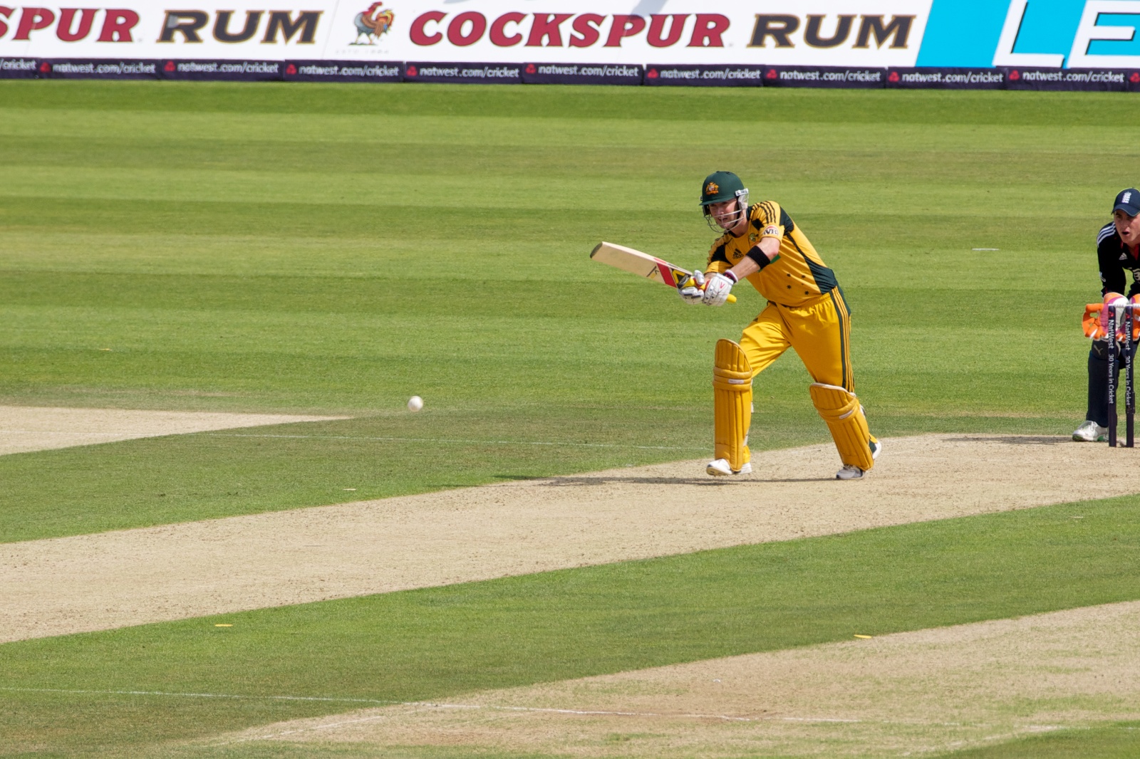a man in yellow playing cricket on a field
