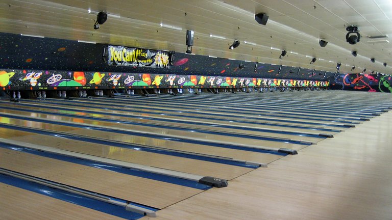 a row of bowling lanes filled with blue bowling balls