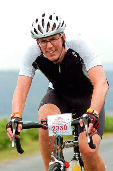 a man with glasses riding a bike down the road