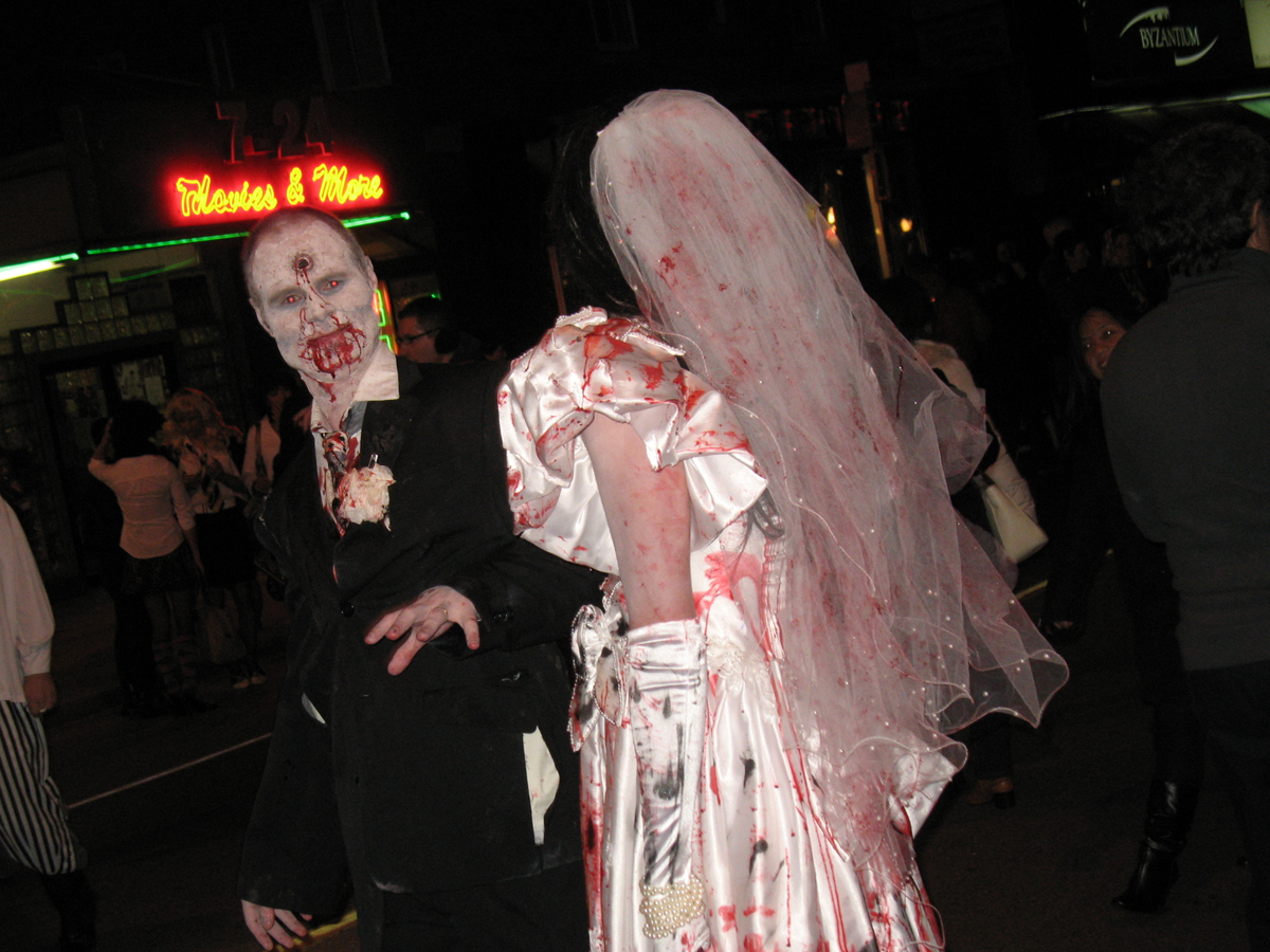 two zombie brides with  on their faces walking down the street