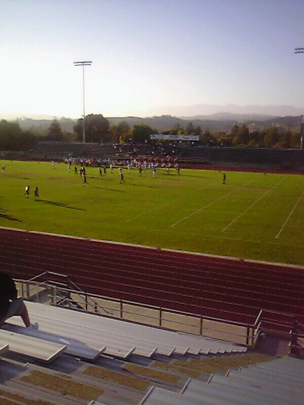 a person crouches in a stadium with other people playing football