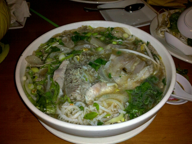 an enormous bowl of noodle soup with a spoon on the side