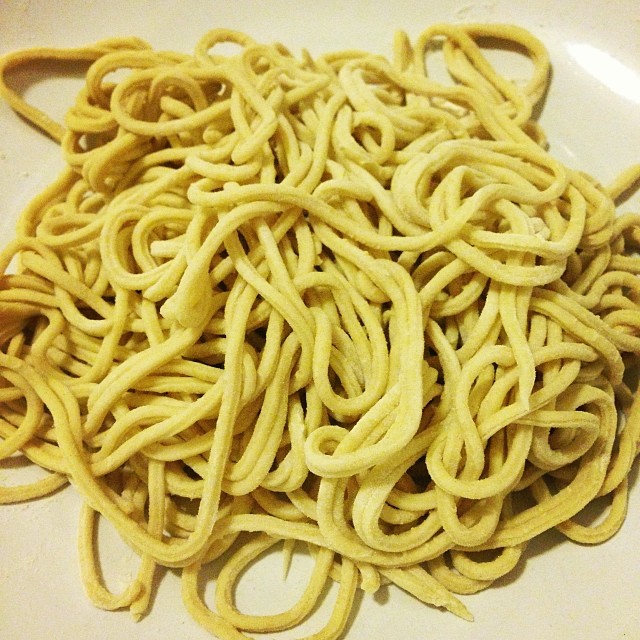 a white plate holding cooked and uncooked noodles