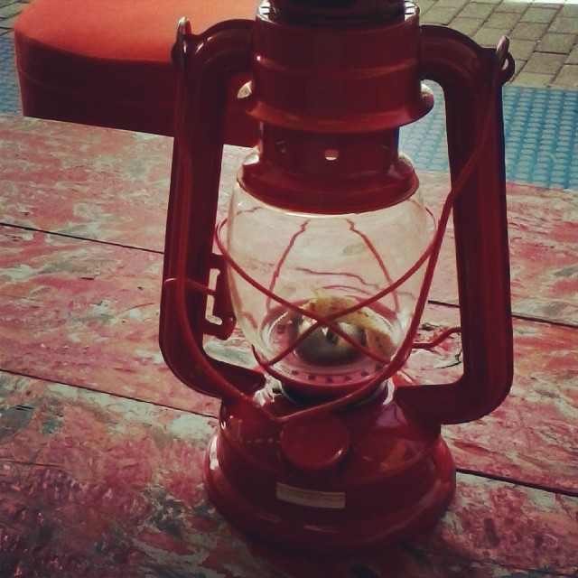 a red lantern with a glass base on a patio