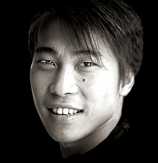 black and white po of man smiling with a dark background