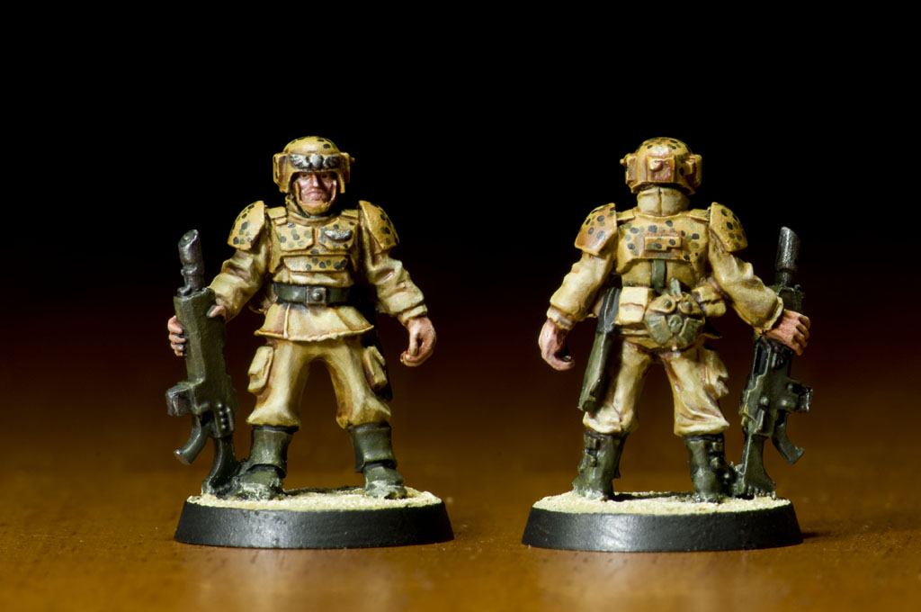 two plastic soldiers stand on a table with weapon